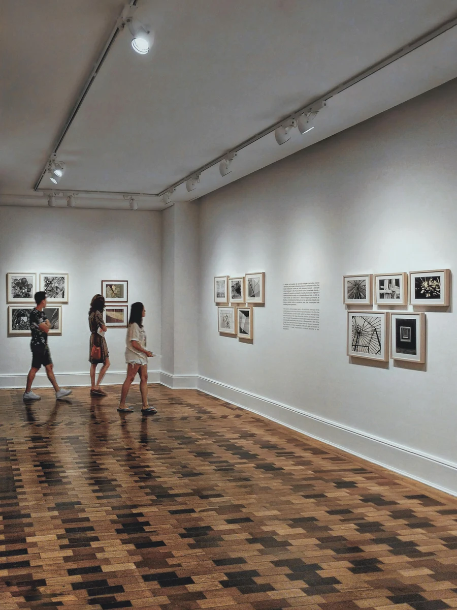 Visitors looking at artworks in a quiet museum gallery.